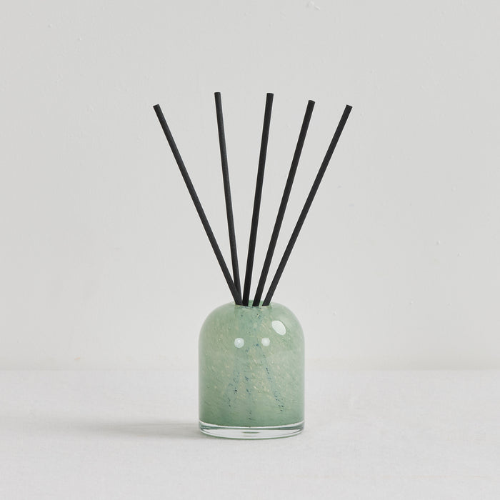 Aurora Diffuser - Mandarin Spice reed diffuser in a soft green glass vessel with black reeds