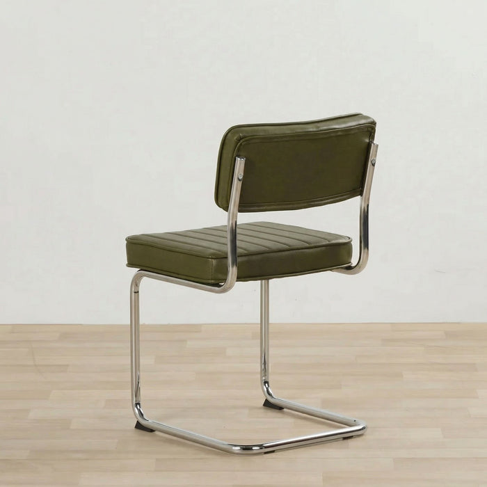 Green chair with metal frame on a wooden floor and light gray background