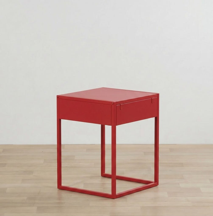 Red side table with a drawer on a wooden floor and light gray wall background