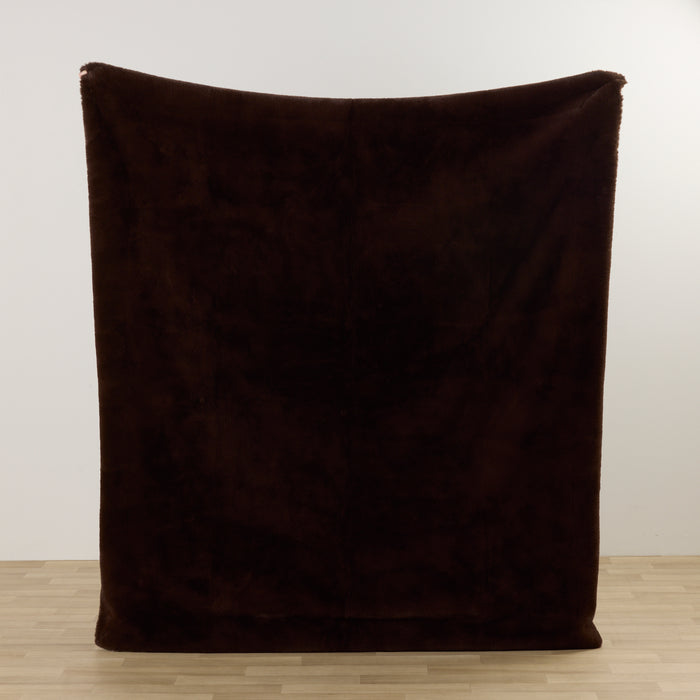 Brown blanket on a wooden floor with a white wall background