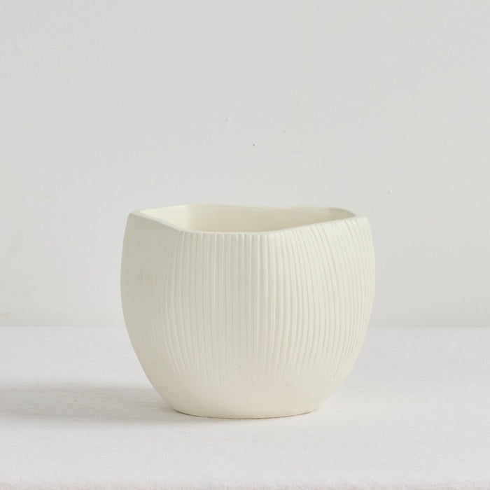 White ceramic pot with textured surface on a light gray background