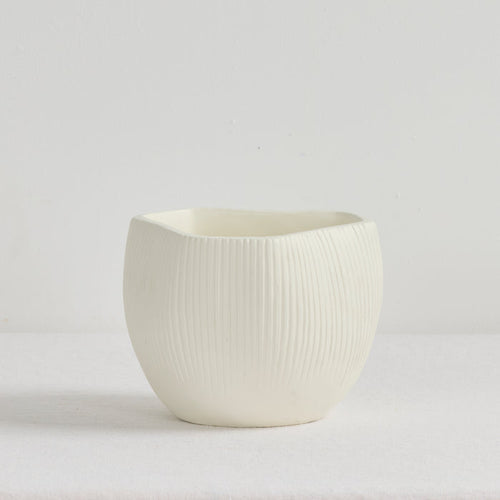 White ceramic pot with textured surface on a light gray background