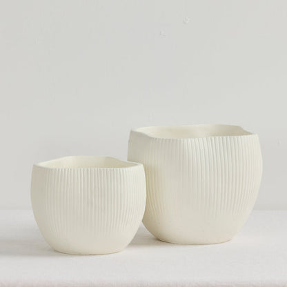 Two white ceramic pots with textured surfaces on a light gray background
