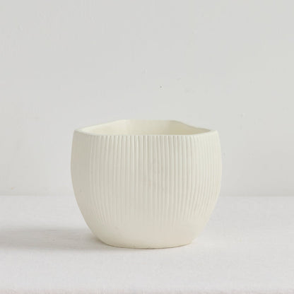 White ceramic pot with ribbed texture on a light gray background