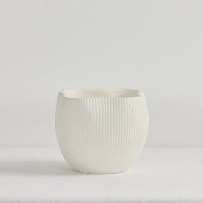 White ceramic cup with ribbed texture on a light gray background
