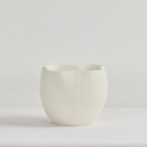White ceramic cup with ribbed texture on a light gray background