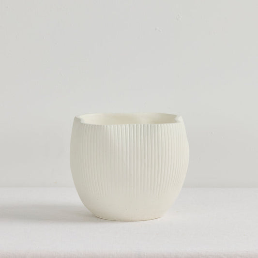 White ceramic cup with ribbed texture on a light gray background