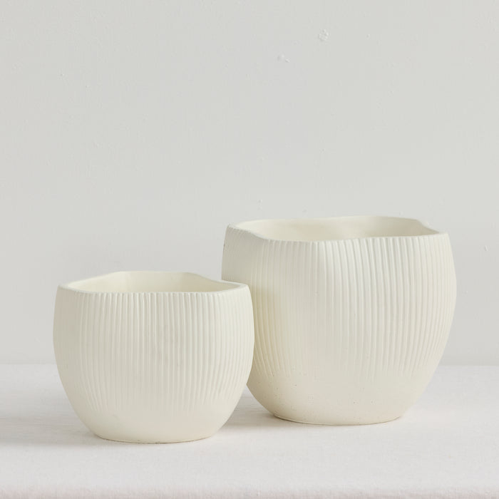 Two white ceramic pots with textured surfaces on a light gray background