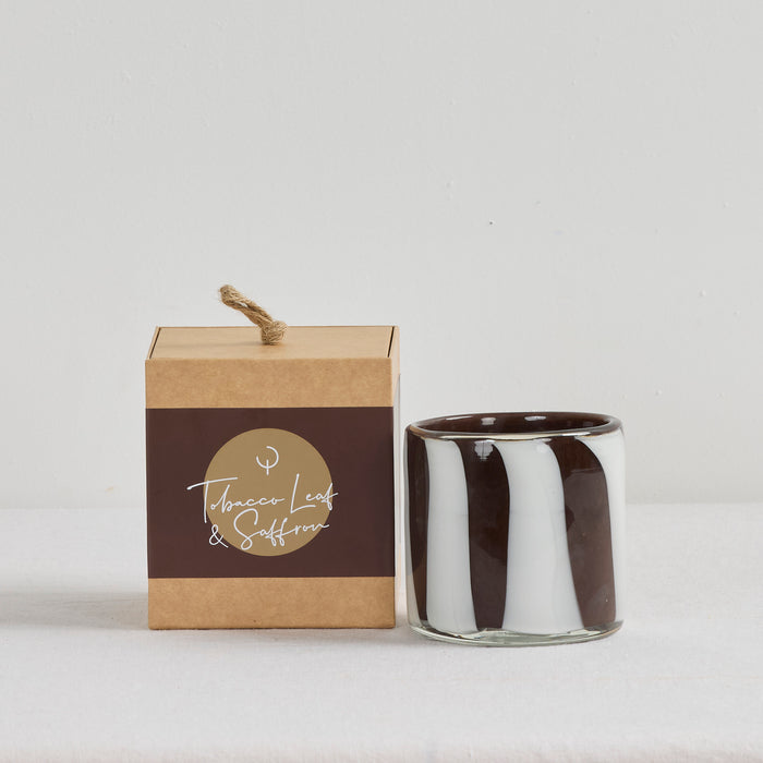 Aurora Candle - Tobacco Leaf & Saffron, organic brown and white striped glass vessel beside kraft gift box.