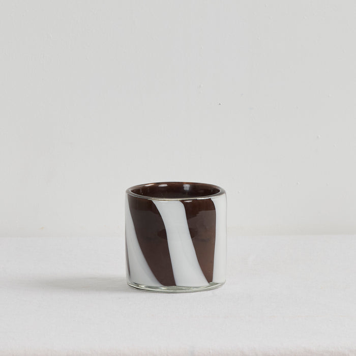 Aurora Candle - Tobacco Leaf & Saffron in a brown and white organic striped glass vessel on a white surface