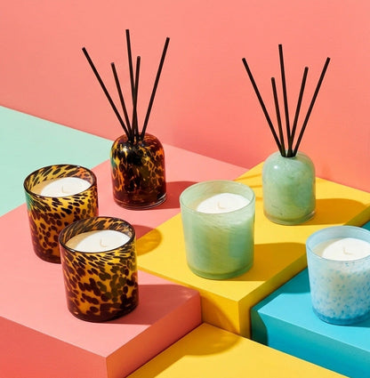Aurora Diffuser - Crème Caramel & Custard tortoiseshell glass reed diffuser styled with colourful candles on geometric blocks