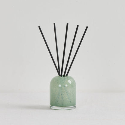 Aurora Diffuser - Mandarin Spice reed diffuser in a soft green glass vessel with black reeds