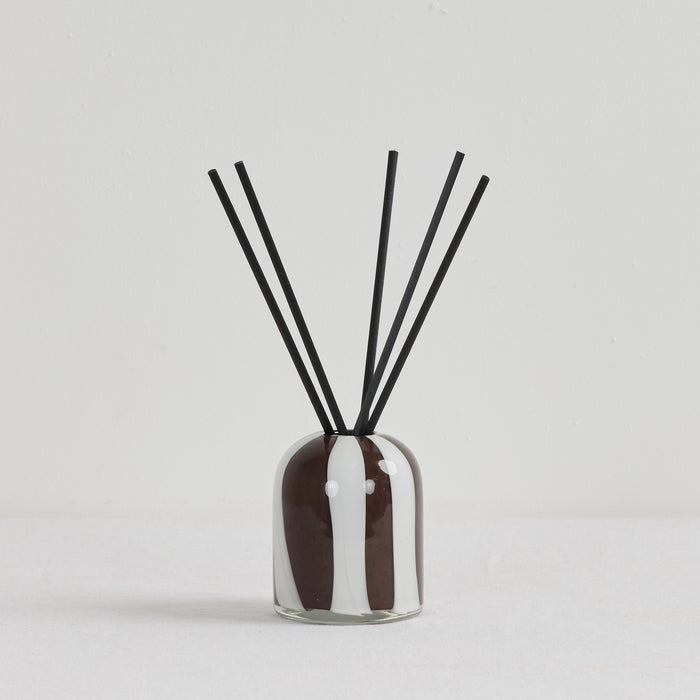 Aurora Diffuser - Tobacco Leaf & Saffron reed diffuser in an organic striped glass vessel with black reeds