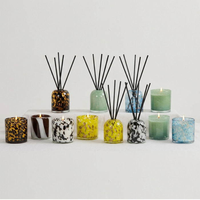 Aurora Diffuser - Tropical Crush yellow mottled glass reed diffuser with black reeds, styled among colourful candles and diffusers