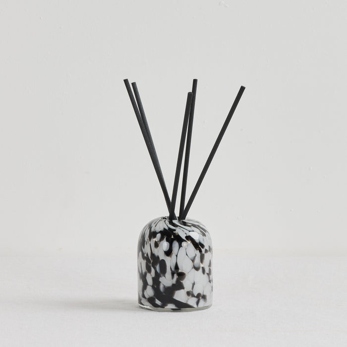 Aurora Diffuser - Vanilla Passionfruit reed diffuser in a mottled black, white and grey glass vessel with black reeds
