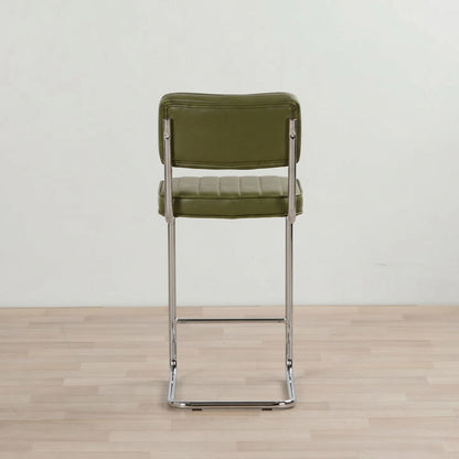 Green bar stool with metal frame on a wooden floor and light gray wall background