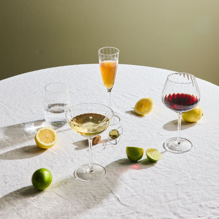 Assorted cocktails in glasses with lemons and limes on a white tablecloth.