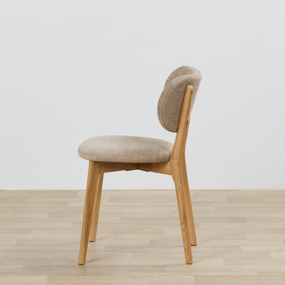 Chair with beige cushioned seat and backrest on a wooden floor with a light gray background