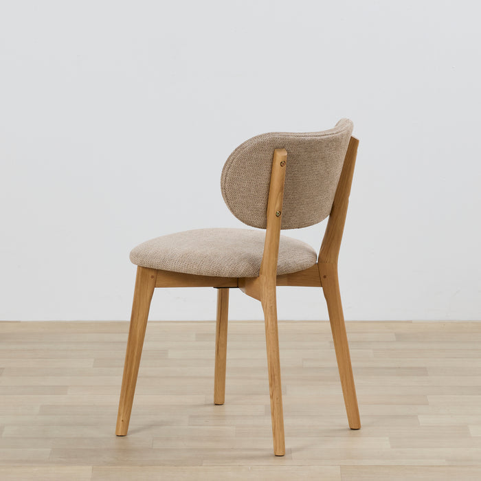 Chair with wooden frame and beige cushioned seat and backrest on a light wooden floor.