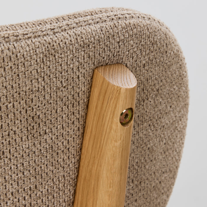 Close-up of a textured beige chair arm with a wooden armrest on a light gray background