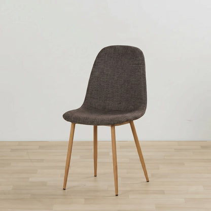 A modern dining chair with a textured dark brown upholstered seat and backrest, supported by four tapered light wood legs, set against a minimalist off-white wall and light wood floor.