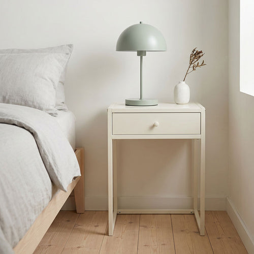 Minimalist bedroom with a nightstand, lamp, and vase.