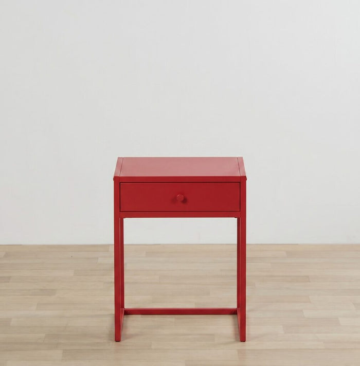 Red side table with a drawer on a wooden floor and light gray wall background
