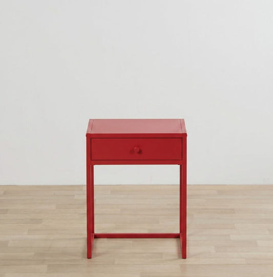 Red side table with a drawer on a wooden floor and light gray wall background
