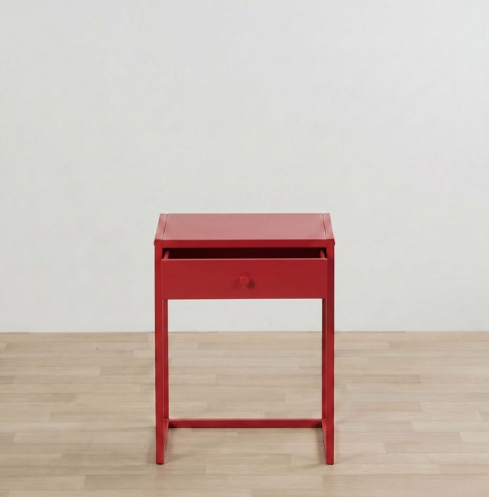 Red side table with a drawer on a wooden floor and light gray wall background