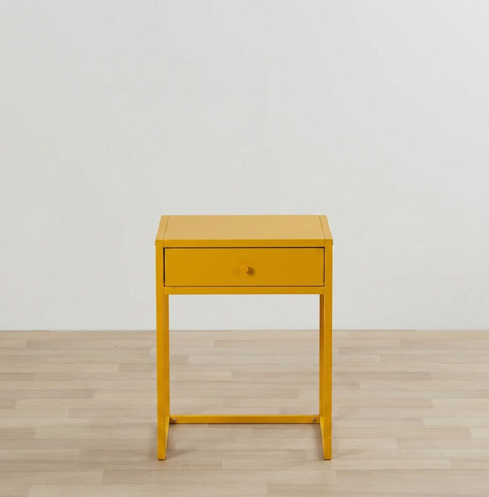 Yellow side table with a drawer on a wooden floor and light gray wall background