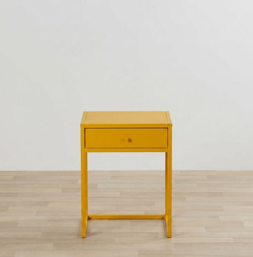 Yellow side table with a drawer on a wooden floor and light gray wall background