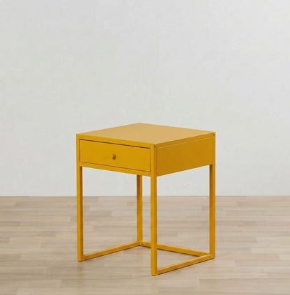 Yellow side table with a drawer on a wooden floor and light gray wall background