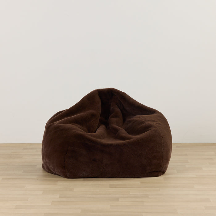 Brown bean bag chair on a wooden floor with a white wall background