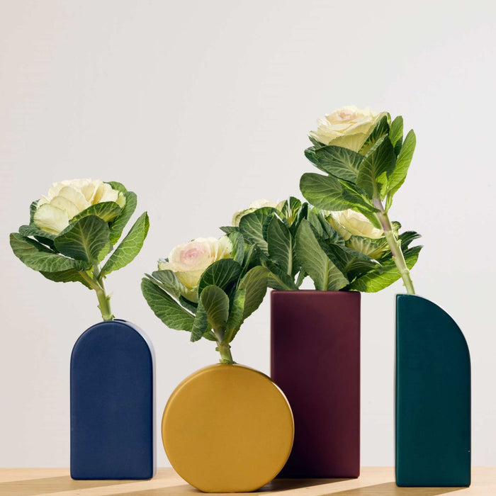 Little Round Vase - Yellow, a small round yellow ceramic vase styled with leafy white flowers among colourful vases