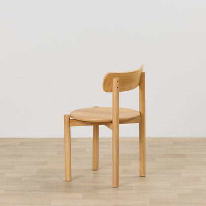 Maeve Dining Chair - Natural, solid wood dining chair with rounded seat and curved backrest, viewed from the side on timber flooring