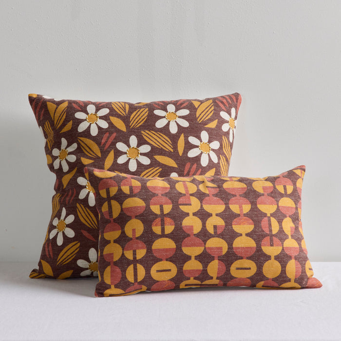 Two decorative throw pillows with retro patterns in brown, yellow, and white, displayed against a neutral light gray background.
