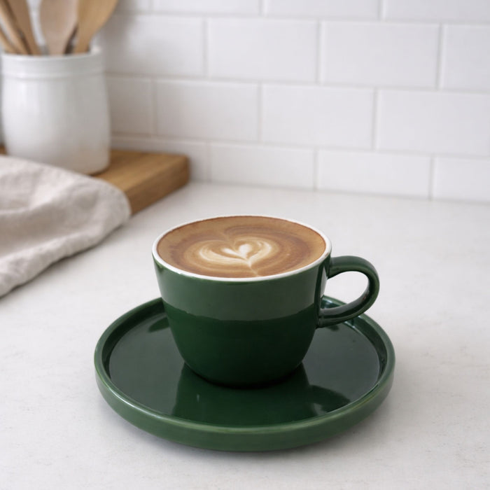 Green coffee cup with cappuccino on a white countertop