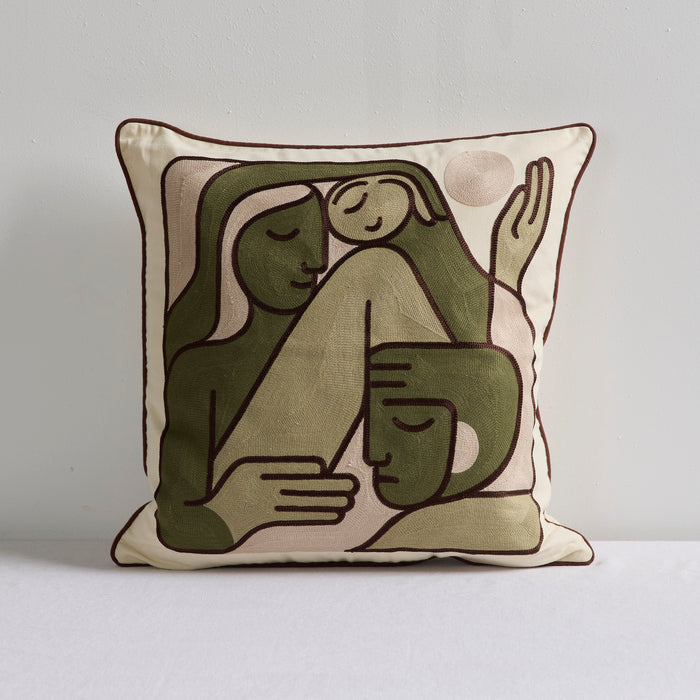 A square decorative throw pillow featuring a minimalist, stylized illustration of two embracing figures in muted olive green and beige tones with dark brown outlines, set against a plain light gray background.