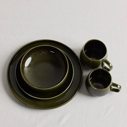 Green stacked dinnerware with green mugs on a white tablecloth