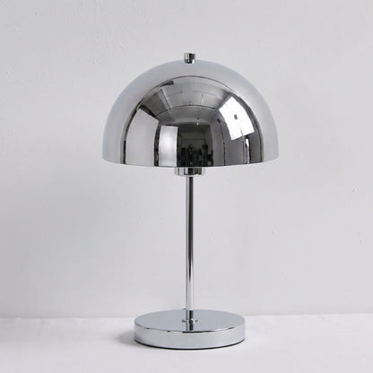 A polished chrome table lamp with a dome-shaped shade, a slim central stem, and a round base, set against a plain light gray background.