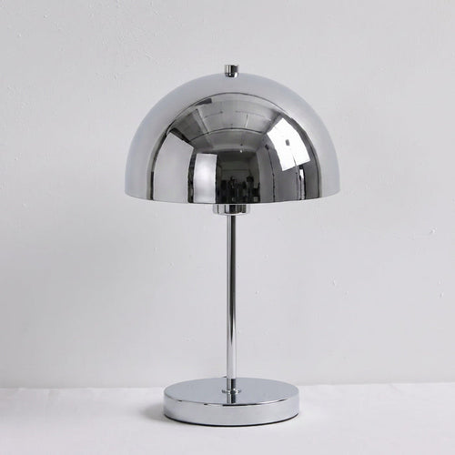 A polished chrome table lamp with a dome-shaped shade, a slim central stem, and a round base, set against a plain light gray background.