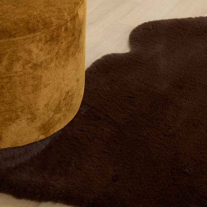 Brown textured ottoman and rug on a light wooden floor