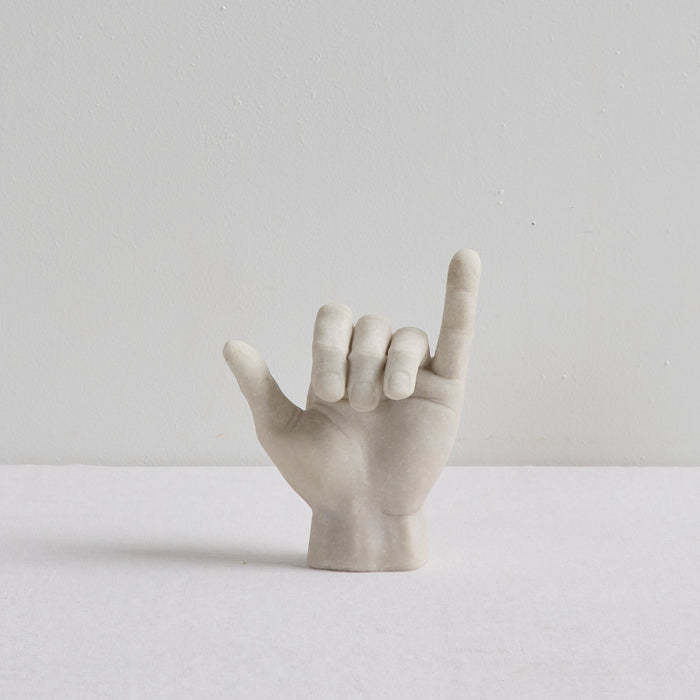 Shaka Hand Object - Bone sculptural ornament in a playful hang loose hand gesture on a white surface