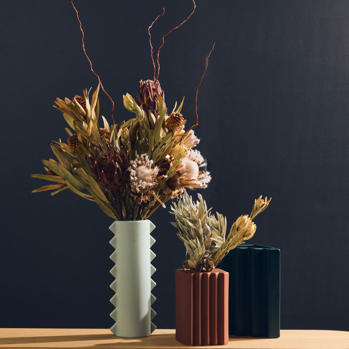 Stria Triangular Vase - Green, deep green ceramic vase with angular fluting, styled with dried foliage alongside decorative vases