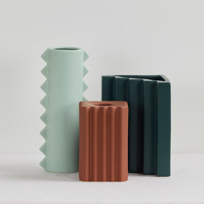 Stria Triangular Vase - Green, deep green ceramic vase with angled vertical fluting, styled with contrasting sculptural vases