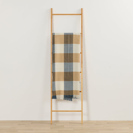 Tara Throw - Blue/Tan checked throw with fringe draped over a timber ladder in a minimalist room.