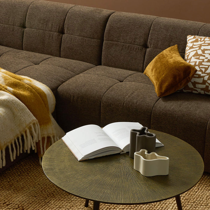 Brown sectional sofa with a coffee table featuring an open book and decorative items.