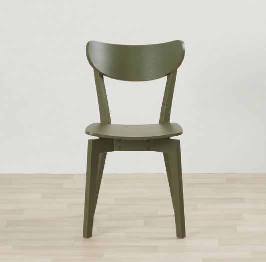 An olive green molded wood dining chair with a curved backrest and tapered legs, set against a minimalist white wall and light wood plank floor.